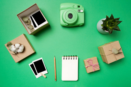 Flat lay analog camera, photos, photos in the box, boxes, notepad, pencil, succulents on green background. High quality photoの写真素材