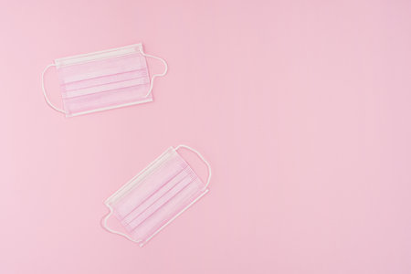 Pink masks on pink paper background creative concept. Flat lay isolated on pink. High quality photoの写真素材
