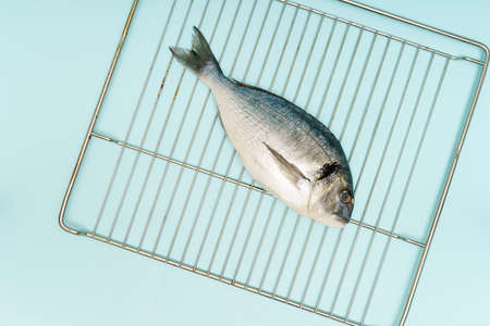 F Flat lay fresh raw dorado fish cooking home on metal grid on blue background. High quality photoの写真素材