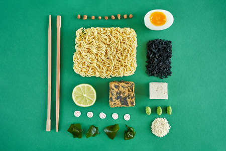 Flat lay concept ramen soup ingredients noodle, egg, wakame algae, lime, tofu, soy meat and chopsticks on green background. High quality photoの写真素材