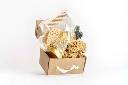 Natural sea sponges, soup, cosmetic bottle with oil or serum in craft box on white. Creative concept...