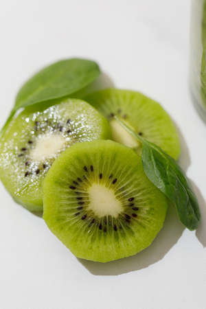 kiwi slices and spinach leaves close up in the sunlightの写真素材