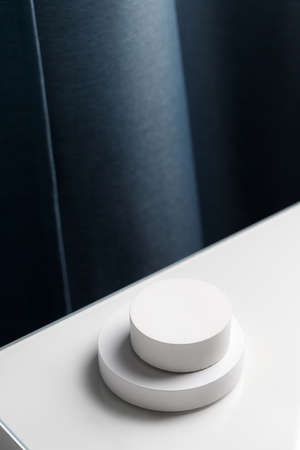 Two White podiums on white table on a background of blue curtains. Podiums for presentation and cosmetic. white pedestal. minimalisticの写真素材