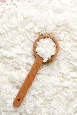 Spoon with Organic white soy wax flakes for candles and sachet. Flat lay, top view. Natural soy and...