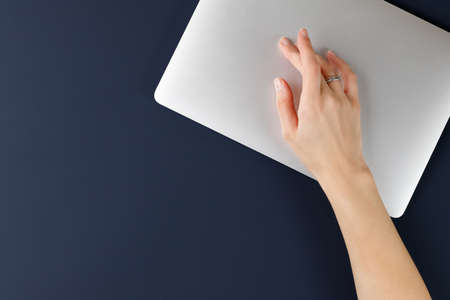 Hand over laptop working space on blue background. top view. Distant work.