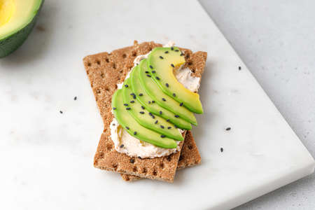 Avocado on wholewheat toast with sesame seeds on marble white board