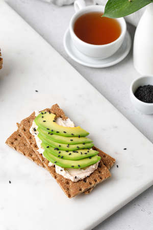 Breakfast with avocado toast with wholemeal bread with black sesame seeds on marble board. cup of tea.の写真素材