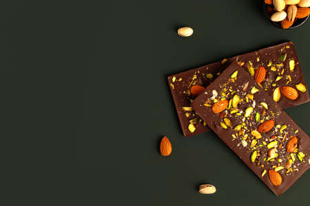 Sweets, confectionery. Chocolate with pistachios and almond, on green background. copyspace.の写真素材