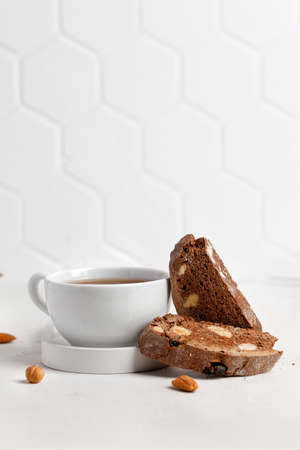 Italian chocolated cantucci with almond and hazelnuts. Biscotti cookies with nuts and cup of tea. Homemade biscotti. White background, tiles.の写真素材