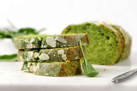 Green cake with Flaked almonds cutted on marble board. Pieces of Sponge green pie with spinach.の写真素材