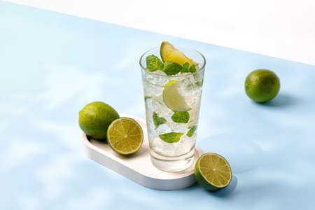 Delicious refreshing summer mojito with ice, lime and mint in a glass with grops. Sunshine....