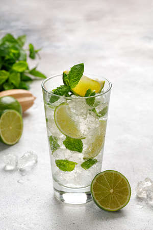 One glass with cold mojito with ice, lime and mint. Fresh Lemonade, tonic on gray background