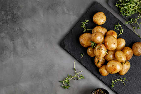 Young Fresh homemade baked baby potatoes with thyme on slate board and dark background. Top view, copy space, text place.の写真素材