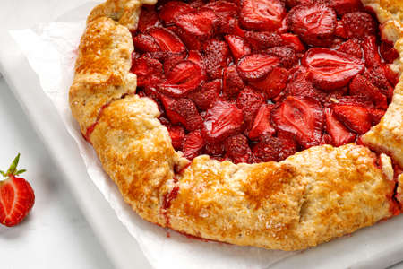 Open strawberry pie on marble board. Strawberry galette. Homemade pastry, baked galette with strawberry. close up.の写真素材