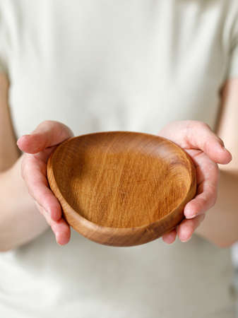 Empty oval wooden oak plate, dish in woman hands. Empty and template mockup with place for food. Kitchen utensils.の写真素材