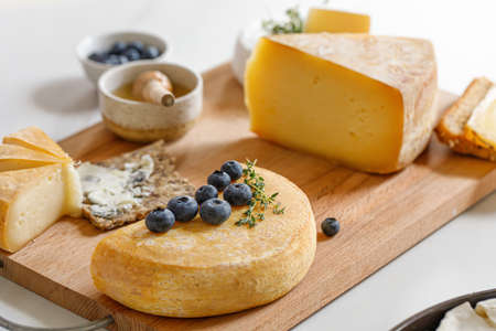 French and Italian cheeses. Reblochon cheese with honey and Blueberry. Cheese plate, dish.