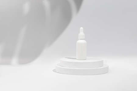Podium, display scene with shadow. Mockup of beauty cosmetic makeup bottle with pipette product on round white platform, stand to show cosmetic product on white background.の写真素材