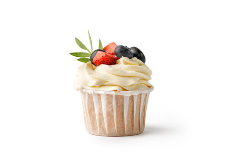 Vanilla cupcake with cream decorated with berries and green leaves isolated on white background. Delicious homemade dessert. Festive bakery.の写真素材