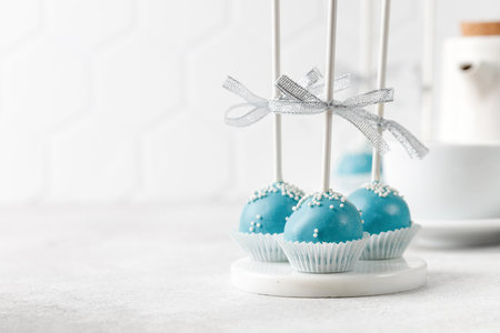 Cake pops on sticks. Set of blue cake pops with cup of tea on gray background. Sweet homemade dessert. Copy space, text place.の写真素材