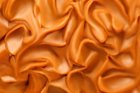 Liquid melted caramel syrup. Background of caramel syrup, paste. Curl, wave of caramel. Texture, Close up, top view. Toffee.の写真素材