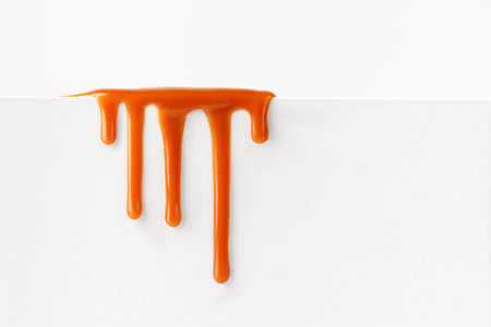 Dripping caramel drops of sweet caramel sauce isolated on white background. Melted caramel sauce drip, drops of sweet liquid toffee.の写真素材