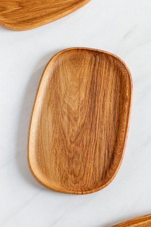 Empty oval wooden plate on kitchen table. Wooden oak dish, board, tray. Empty and template mockup with place for food. Kitchen utensils. top view.の写真素材