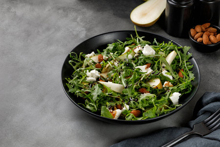 Diet salad with green arugula, feta cheese and pears, almond nuts. Delicacy fresh Green fruit salad on dark background.の写真素材