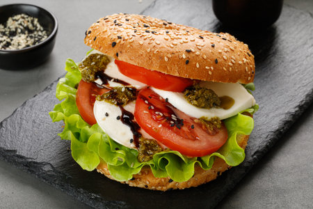 Sandwich, toast, bagel with mozzarella cheese, pesto sauce, tomatoes. Caprese Sandwich on black...