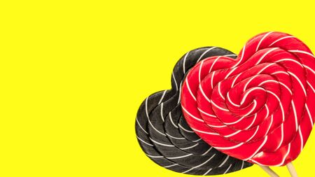 multicolored heart-shaped lollipops on a bright yellow backgroundの写真素材