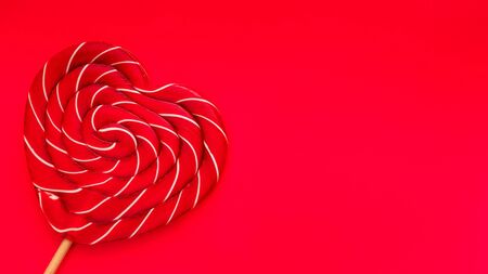 red heart-shaped lollipop on bright red backgroundの写真素材