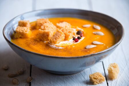 Delicious pumpkin soup in a bowl with croutons on white woodの写真素材