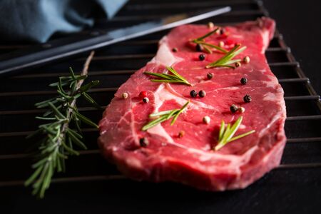 Raw reef meat, uncooked steak with rosemary, lemon and spices, ready to cook