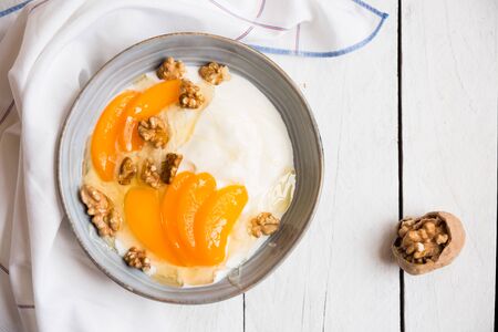 Yogurt with peach, nuts and honey in a blue bowlの写真素材