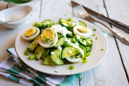 Healthy green salad with cucumbers, eggs, onions and creamの写真素材