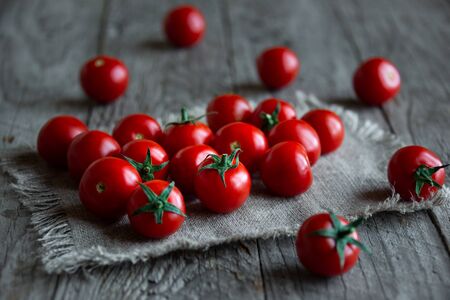 Fresh ripe organic cherry tomatoes on dark wooden backgroundの写真素材