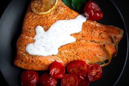cooked salmon fish with lemon and cherry tomatoes on dark backgroundの写真素材