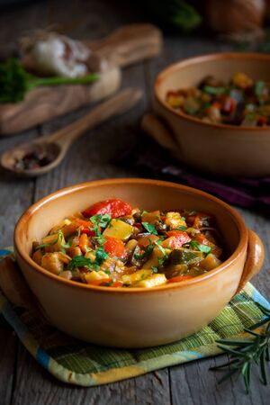 Chopped cooked vegetables on dark wood. ratatouille with zucchini, bell pepper and eggplantの写真素材