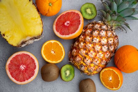 Ripe pineapple and other fruit - orange, kiwi, grapefruit on grey backgroundの写真素材