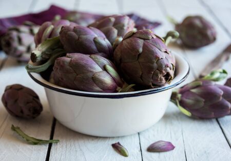 Fresh uncooked artichokes vegetables in a white bowl, healthy food conceptの写真素材