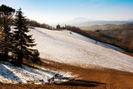 Countryside landscape in autumn with snow, agricultural fields among hillsの写真素材