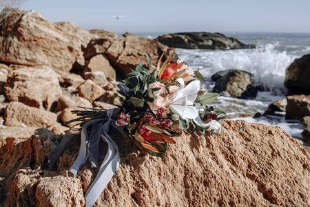 Beautiful bouquet of flowers. A wedding bouquet lies on a stone near the sea. Rocks near the Black Seaの写真素材
