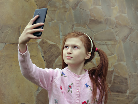 A girl is taking the selfy with a smartphoneの写真素材