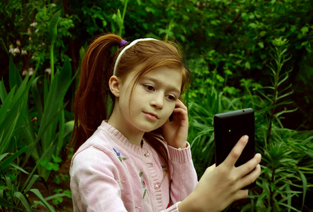 A girl is taking the selfy with a smartphone in a gardenの写真素材