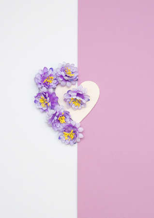 Gift box with satin bow and five blue flowers around. Flat lay on pastel rose background.の写真素材
