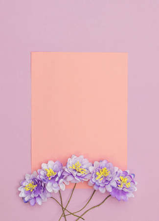 Gift box with satin bow and four blue flowers on violet background. Orange paper note.の写真素材