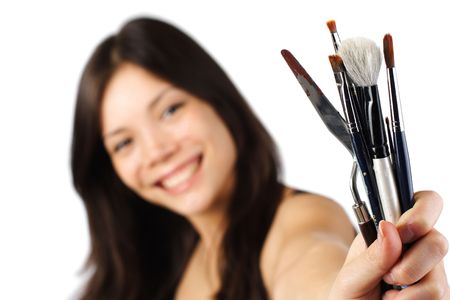 Beautiful young painter showing brushes. Shallow depth of field, focus on brushes. Isolated on white background.の写真素材