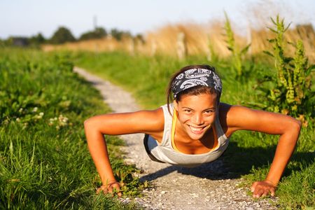 Mixed woman doing push-ups during outdoor exercise a summer night in denmark