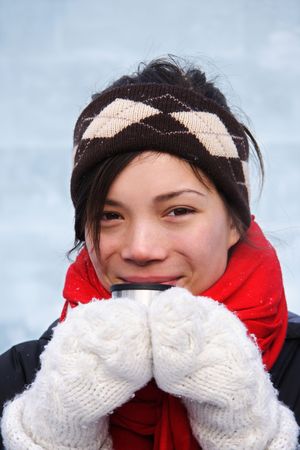 Cold winter woman getting warm drinking a hot drink. Ice wall background.