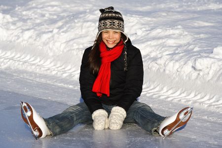 Ice skating. Young woman sitting on the ice, while skating outside on a sunny winter day in Quebec City.の写真素材