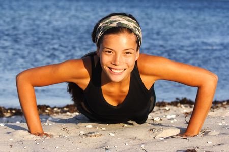 Attractive woman doing push-ups on the beach.の写真素材